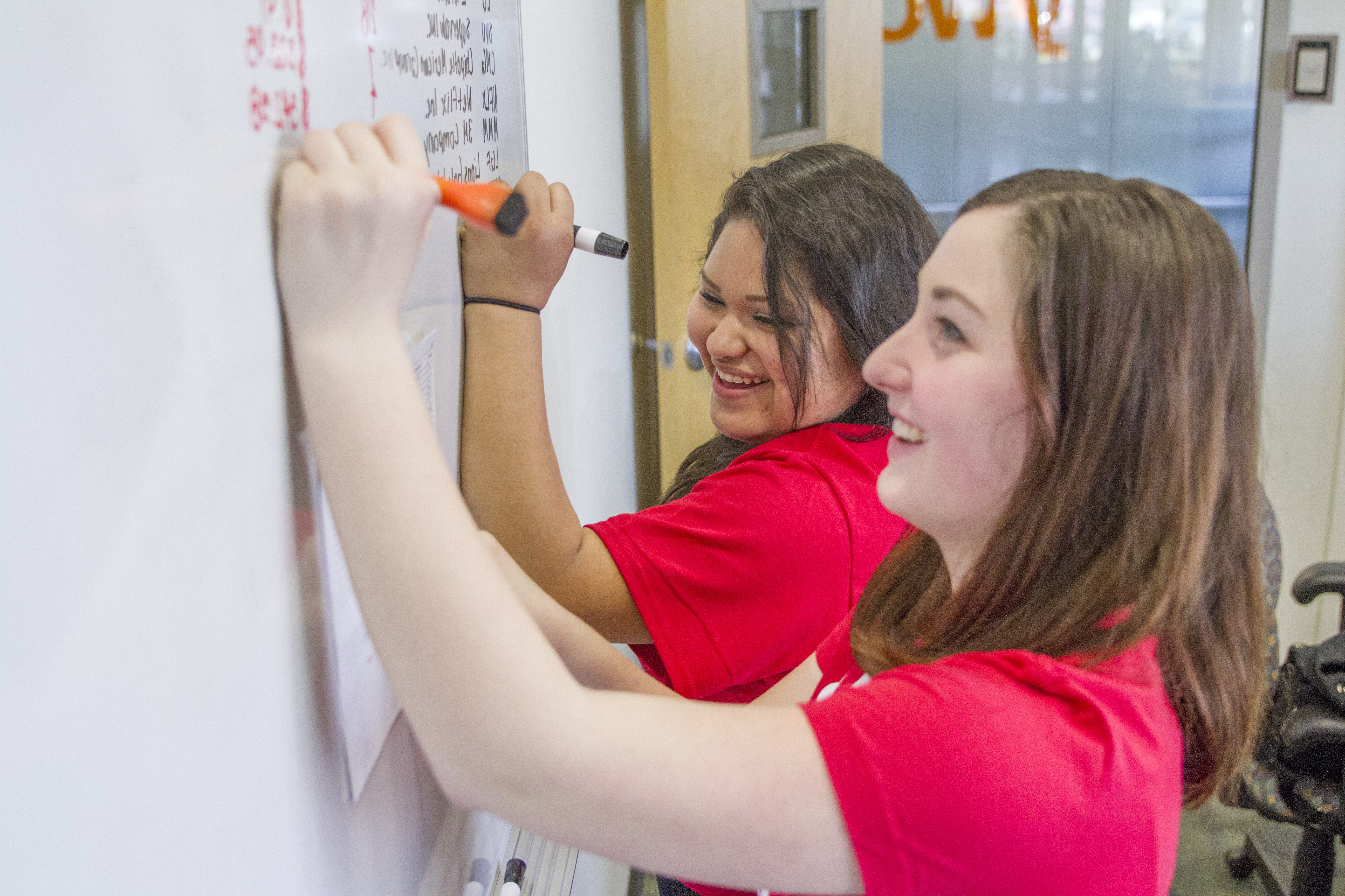 2 women writing on a white board